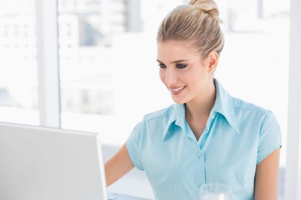 Cheerful well dressed businesswoman in bright office using laptop