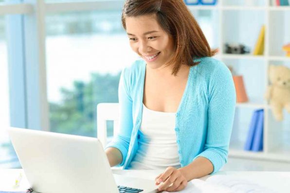 Copy-spaced image of a young lady networking at home while doing her homework on the foreground